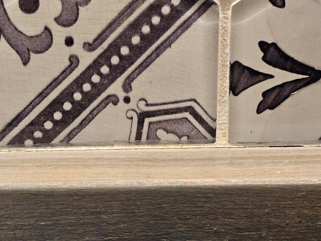 the wooden countertop below the ceramic tile.