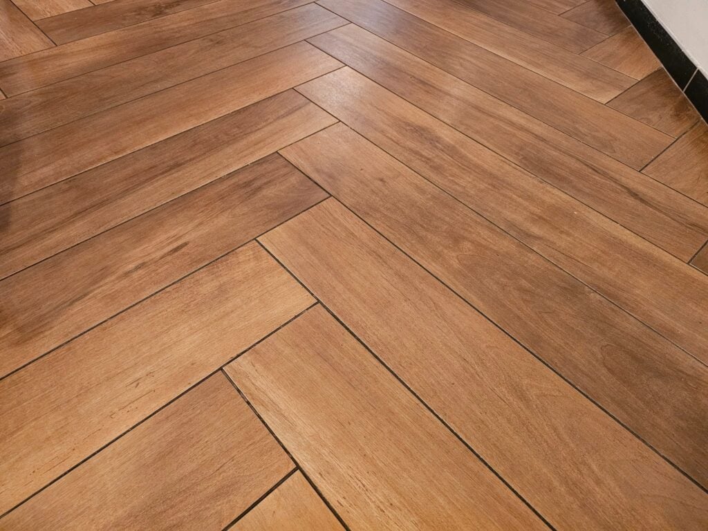 Detailed view of a herringbone wood-like tile installation with seamless grout lines