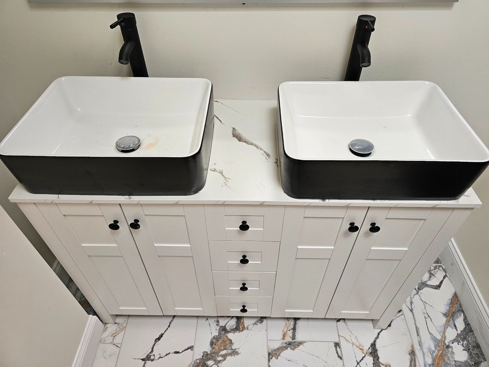 Luxury black and white bathroom vanity installation with matching mirror and modern fixtures