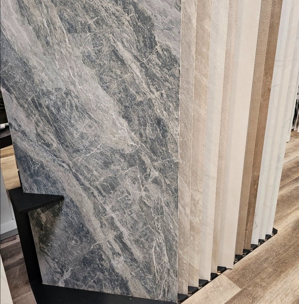 We've looked at a wide range of different of tile here on our website. In some cases we've looked at small mosaics used in backsplashes, shower niches, shower floors, and even in wall areas on bathrooms and kitchens. We have also looked at the more common medium format tiles which generally range between a few inches wide and a few inches tall up to about 12 to 18 inches in their longer span. Today we're looking at something similar but a bit different. We are looking at examples of large format tiles. These tiles are generally between a few feet wide and several feet long. This past week, for example, we looked at hexagonal tiles that were about 6 inches across from perpendicular edge to perpendicular edge and about 7 inches across from point to point in their longest dimension. In contrast, the tiles shown in the picture below are much larger. These tiles are 24 inches wide x 48 inches tall, in their current position. Here, as shown below, they are just sat onto a display rack where it can be selected for purchase. In this display, several different tiles of similar shape and size are positioned together for presentation. We often talk about porcelain and ceramic materials as being similar, sometimes we use the words interchangeably, depending on the nature of the tile. Here though, the difference has a specific distinction. These are porcelain tile and natural stone tiles as well. By comparison, natural stone cannot be cut quite so thin at such a large span. As well, ceramic, at this large width, lacks the intrinsic strength resistance to remain structurally stable. Although these particular tiles, above, are shiny, they're acceptable to be used both on floors and walls. Often, we will suggest using a tile material that has a bit more texture on the exposed surface if it's going to be used for flooring. Even these tiles, although made to be used in both types of surfaces, can become dangerously slippery when wet. Outside of kitchens and bathrooms, it's not as common for floors to be excessively wet. So therefore, in non wet areas, clients may choose to use a tile material like this. The picture below shows a selection of ceramics and vitrified porcelain floor tiles. The technical, scientific difference between ceramics and vitrified porcelain floor tiles is both the composition and the firing methods. Both porcelain and ceramic are fired to become at least partially vitreous. Essentially, cooking these formed materials at extremely high temperatures changes their chemical composition. At higher temperatures, for longer periods of time, they've become more similar to glass. A firing that is on the spectrum towards that level of vitreousness, in some cases, be referred to as semivitreous. Standard ceramic generally contains a higher proportion of coarse,natural red or white earthenware substrate components. This is a type of unrefined clay blended often with basic naturally occurring minerals. The red variety of clay generally contains a higher ratio of iron oxides. The iron oxides, for example, provide the reddish color found in terracotta and brickwork. These materials are similar, even in ceramics. The pictures below show a large format type of tile that is made to mimic natural marble. Marble occurs naturally in different parts of the world, but is actually a bit rare here within the continental United States. The option shown in the next picture below looks very similar from one to the next. There are differences though. If you look very closely you can see that the hue or shade of the near white or light gray colors is actually a bit different. When designing the precise points of the details of a kitchen or bathroom, it's important to consider these finer details. The next picture below shows different tiles that range in color from a light and warm color to a dark and cold gray. These particular tiles are large format but are made to look like natural wood. We've looked at other examples of natural wood type embellishments, they may look somewhat convincing at a glance but the difference can generally be discerned when you look closely. The next picture below says another group or selection of large format tiles that look like natural stone. These are similar to the other ones we looked at above but show a different range of colors and designs. Dupont Kitchen & Bath Can Help As dedicated and local DC metropolitan kitchen and bath builders and installers, we pride ourselves on turning your visions into reality. Your kitchen and bathrooms can reflect your unique style and be designed with personalized aesthetics. It can be a process from creative designs to the realization of your dream space. Specializing in kitchen and bath construction, we bring expertise and skills to every project. If you're contemplating a renovation, upgrade, or modernization in the local market, we're happy to be your team. Consult with us, and we can start together on a path to redefine and elevate your DC living experience. You can visit our company website at https://dupontkitchenbathdc.com/ Here at our website you will find a simple and convenient web form that you can fill to contact us quickly.